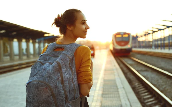 Portrait d'une jeune voyageuse avec un petit sac à dos sur la ligne de chemin de fer — Photo