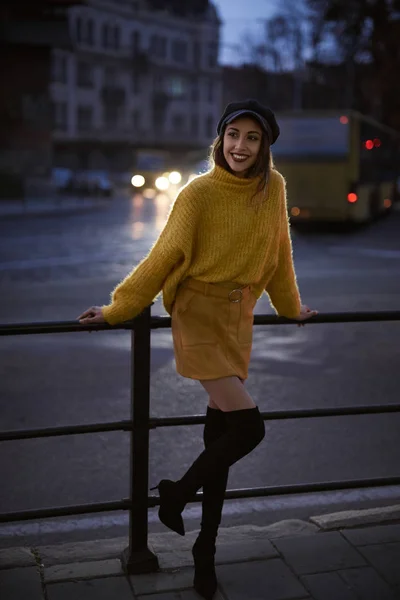 Mooie modieuze vrouw in heldere gele trui en rok en knie hoge hak laarzen wandelen en poseren buitenshuis — Stockfoto