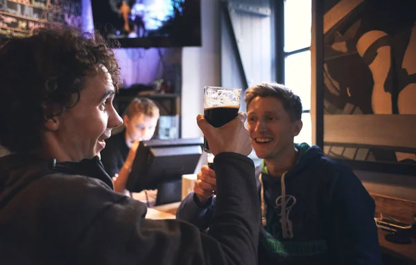 two guys friends sitting in the pub with glasses of beer