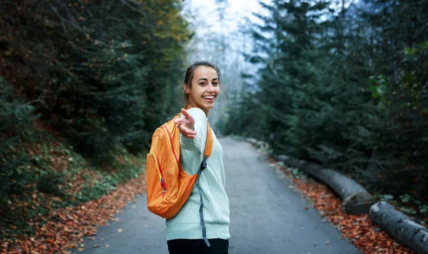 Mujer excursionista con mochila pequeña, de pie en la carretera en el bosque — Foto de Stock