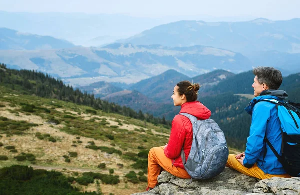 Пара туристів, що сидять на скелі в горах — стокове фото