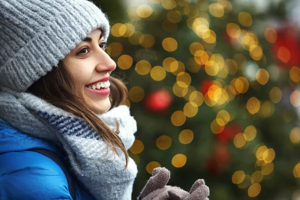 Zbliżenie poziome obrazu s szczęśliwy uśmiechający się kobiety w ciepłe zimowe ubrania na tle jasnego światła Bożego Narodzenia — Zdjęcie stockowe