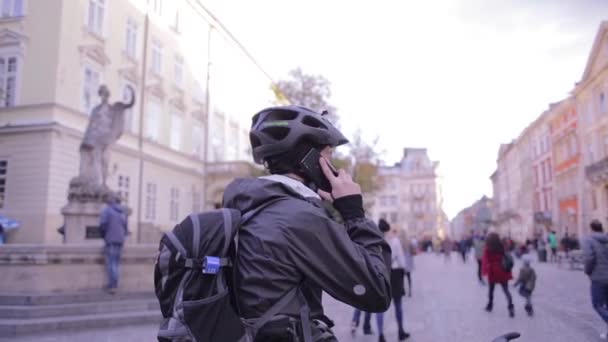 Zadní pohled na cyklista stojící na ulici a mluví o telefonu — Stock video