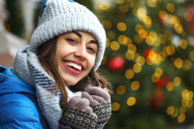 parlak Noel ışıkları arka plan karşı sıcak kış giysileri bir s mutlu gülümseyen kadın closeup yatay görüntü