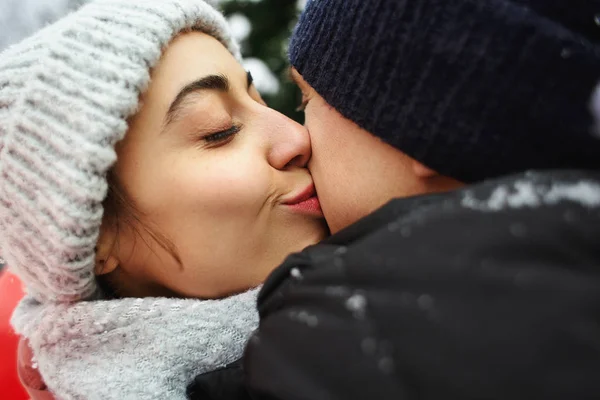 Felice coppia di abbracci in abiti invernali caldi è in piedi all'aperto con un palloncino rosso a forma di cuore — Foto Stock