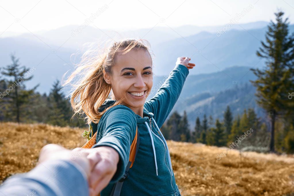 happy attractive woman hiker standing on the mountain slope against background of sunset