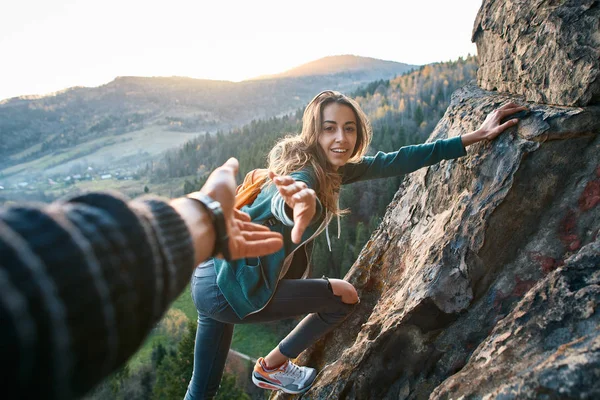 Nainen patikoija kiipesi kalliolle ja saada apua — kuvapankkivalokuva