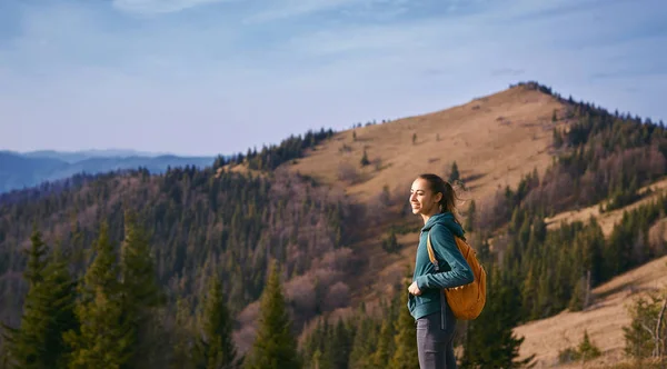 Kuva onnellinen nainen retkeilijä seisoo reunalla vuoren harjun taustaa vasten auringonlaskun — kuvapankkivalokuva