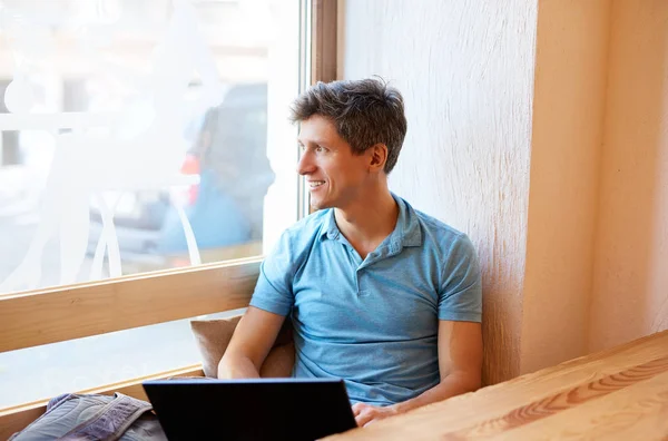 Jeune homme avec ordinateur portable travaillant dans un café — Photo