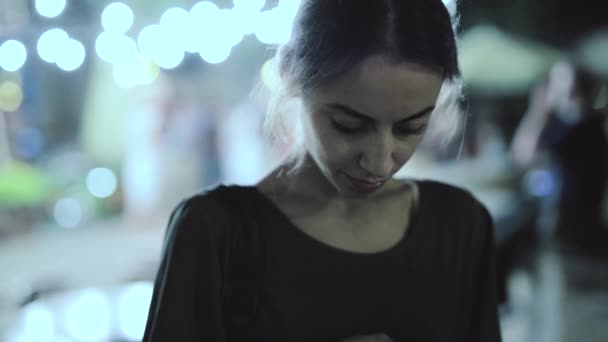 Jonge vrouw staat buiten 's nachts in de stad met behulp van de telefoon. — Stockvideo