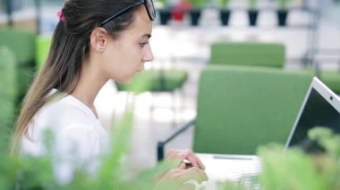 Genç güzel işkadını parlak modern ofis içinde laptop üzerinde yoğunlaşmıştır. İş veya serbest kavramı