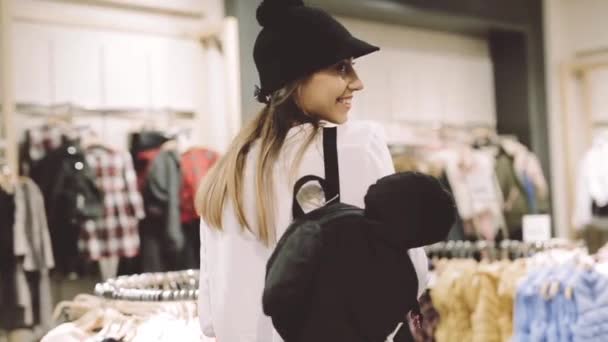 Молодая девушка примеряет шляпу в магазине перед зеркалом — стоковое видео