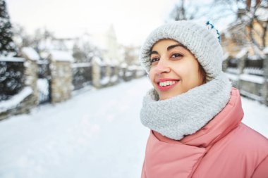 mutlu bir şekilde açık havada yürüyüş soğuk karlı kış gününde mutlu neşeli gülümseyen kadın görüntüsü. ilk kar altında yürüyüş şapka ve atkı örgü pembe kış paltoyla giyen kadın sevinir