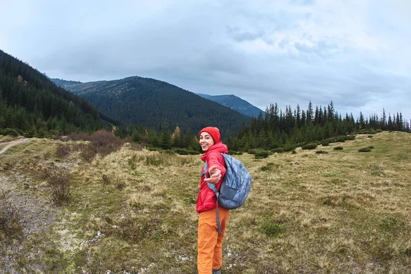 Immagine di una giovane donna escursionista sorridente con piccolo zaino in piedi su un pendio di montagna . — Foto Stock