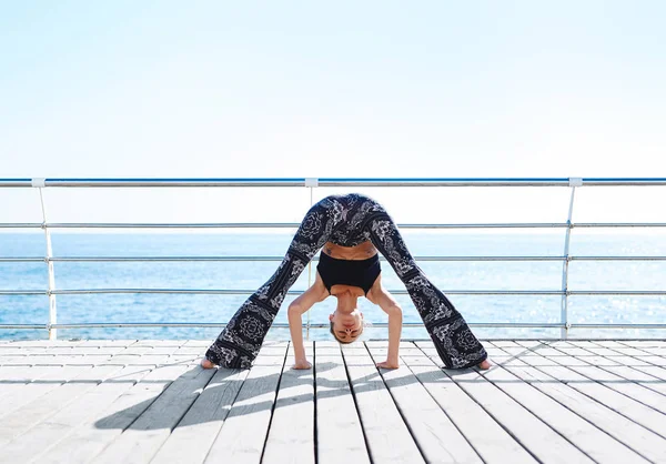 Foto av en ung idrettskvinne gjør yogaøvelser på sjøen . – stockfoto