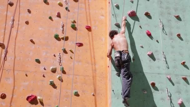 Hombre escalador está escalando en el aire libre escalada gimnasio — Vídeos de Stock