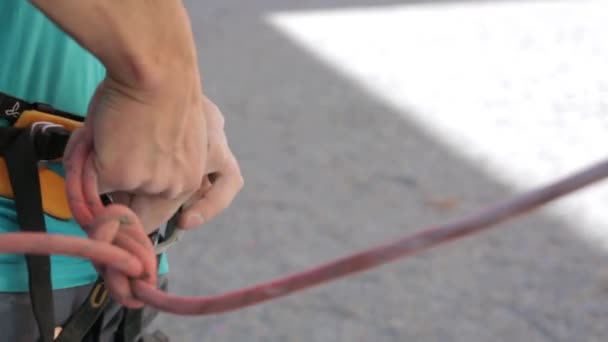 A man climber fasteners rope with carbines to his harness — Stock Video