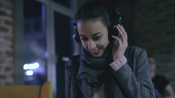 Young pretty woman is listening music in a big professoinal HI-FI headphones — Stock Video