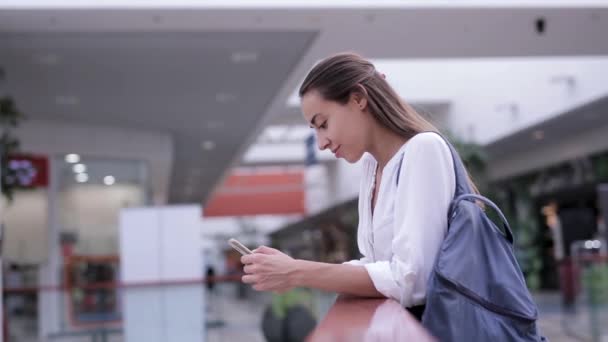 Красива усміхнена жінка приймає вхідний дзвінок на мобільний телефон всередині торгового центру — стокове відео
