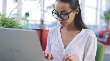 genç güzel Yağız işkadını parlak modern ofis içinde laptop üzerinde çalışıyor