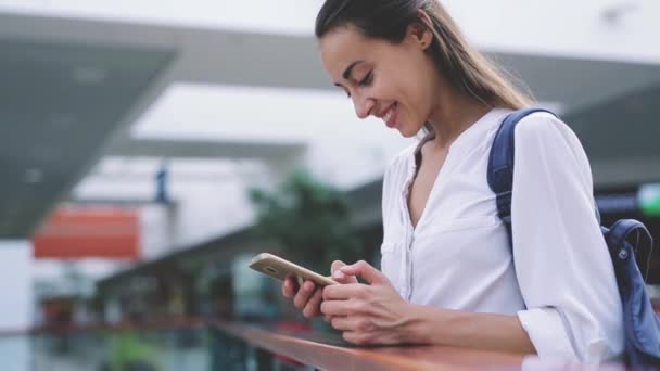 Zaostřená krásné mladé šťastné bělošské ženy s smartphone s poslem — Stock video