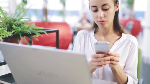 Una donna prende una chiamata in arrivo a un telefono cellulare sul posto di lavoro — Video Stock