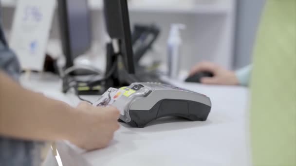 A woman pays a purchase in a store with a bank card using a terminal. closeup womans hands with credit card and terminal — Stock Video