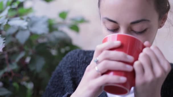 Крупним планом HD стокове відео жінки з чашкою кави. Жінка п'є каву на відкритому повітрі, насолоджується смаком напою і вдихає його смак — стокове відео