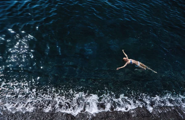 Vista aérea de una mujer flotando y rehaciendo en el mar — Foto de Stock