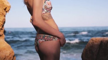 Plajda genç bir gülümseyen kadının portre yakın. Mutlu ince fit vücut kız deniz arka planda ayakta ve kamera bakıyor.