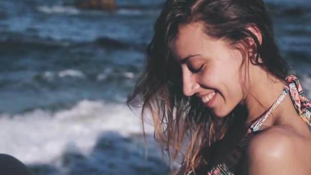 Retrato de cerca de una joven sonriente en la playa. Chica feliz bronceándose en el sol . — Vídeo de stock