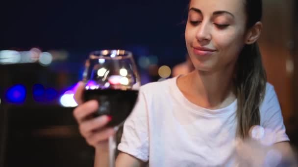 Woman holding a glass of red wine, sniffs it and taste — Stock Video