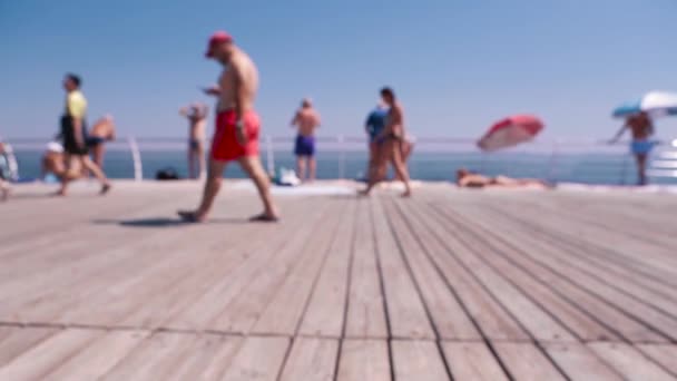 Immagine sfocata del molo di legno e persone che camminano contro un cielo blu brillante nella calda giornata estiva in riva al mare — Video Stock