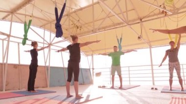 Yoga sınıfı grup yetişkin kadınlar ve bir adam uygulama yoga ve gündoğumu plajda eğitmen ile nefes egzersizleri.
