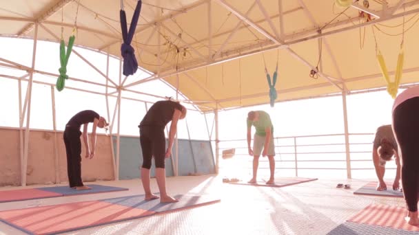 Třída jóda dospělí ženy a jeden muž cvič jómu a dýchají s instruktorem na pláži při východu slunce. — Stock video