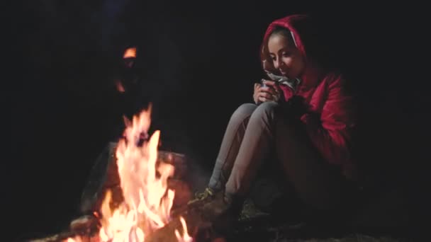 Kamp ateşi yanında oturan genç kadın — Stok video