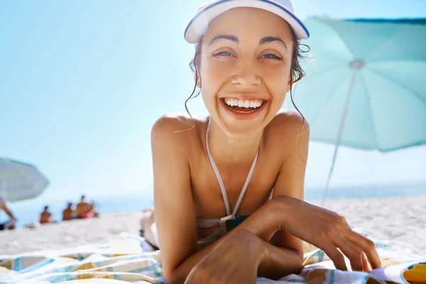 Portrait of beautiful smiling happy woman tanning in white cap on sandy beach at summer. Summer vacation concept. — Stock Photo, Image