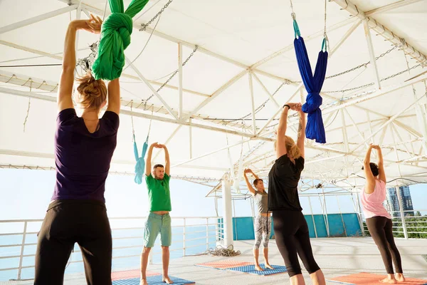 Grupo de personas están practicando fly yoga con una hamaca en estudio al aire libre. Concepto de salud mental y física y armonía . — Foto de Stock