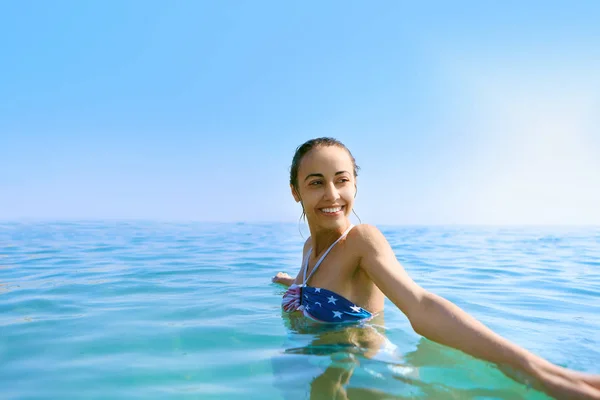 उष्णकटिबंधीय धूप समुद्र तट पर समुद्र में tanned शरीर के साथ एक युवा सुंदर मुस्कुराते हुए महिला का चित्र। ग्रीष्मकालीन अवकाश और टेनिंग अवधारणा . — स्टॉक फ़ोटो, इमेज