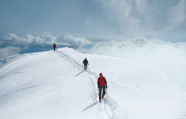 Bir grup dağcı karla kaplı bir dağın tepesine tırmanıyor. Dağcılar dağ zirveleri sırtında yürüyüş vardır. Panorama.