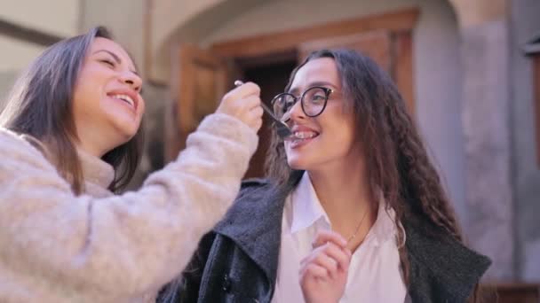 Twee mooie jonge vrouwen zitten aan de tafel in café of restaurant en ontbijten. — Stockvideo