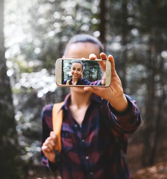 Piękna szczęśliwa stylowa podróżna kobieta biorąc selfie na telefon z kamerą z tłem lasu. — Zdjęcie stockowe