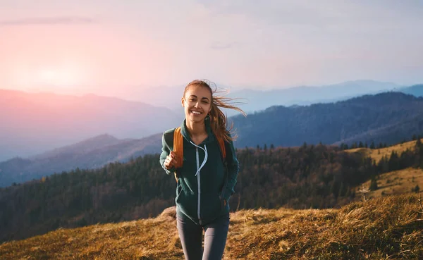 Muotokuva onnellinen nainen retkeilijä seisoo reunalla vuoren harjanteella taustaa vasten auringonlaskun. Matkailu ja aktiivinen elämäntapa . — kuvapankkivalokuva