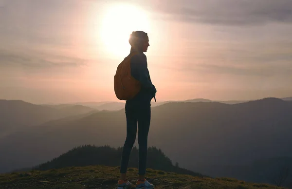 年轻女子站在山边，在夕阳的天空和山背景享受生活剪影. — 图库照片