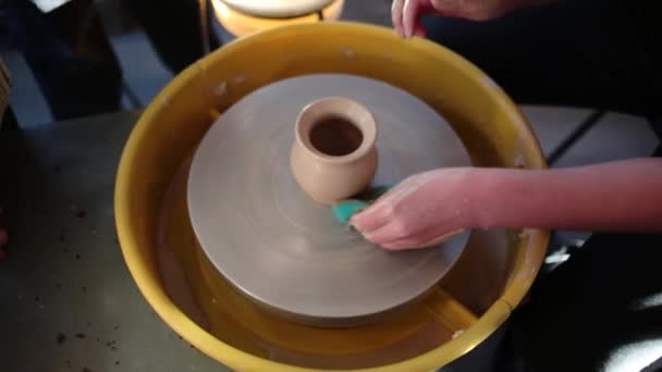 Rueda de alfareros en el taller de cerámica. Artesanía Cerámica dentro. niños Manos trabajando en una rueda de cerámica, formando una olla de barro . — Vídeo de stock