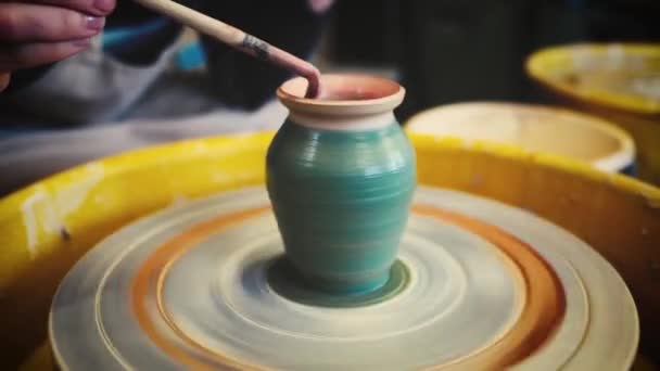 Vasaio femminile dipingere un vaso di argilla su una ruota vasai. Ceramiche artigianali all'interno . — Video Stock