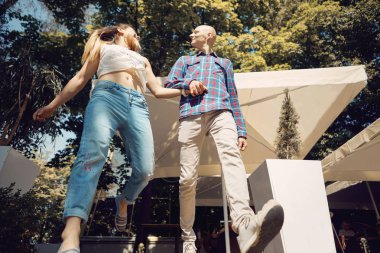 Genç mutlu çift yaz parkında yürüyor. Çift hareket halinde. Alt görünüm.