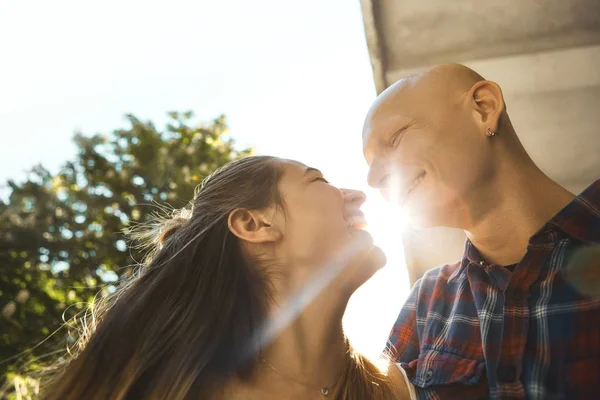 Close up image of happy couple in love, having fun and laughing in park. Young man looks with love at the woman with sun rays background. Top close up view.