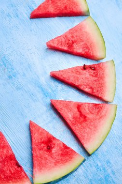 Mavi arka planda üçgen karpuz dilimleri. Üst görünümü kapatın, düz döşeme.