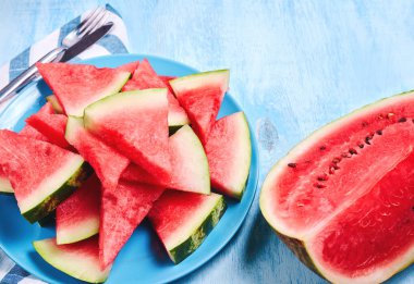 Mavi arka plan üzerinde plaka üzerinde karpuz dilimleri. Üst görünüm, düz yatıyordu.